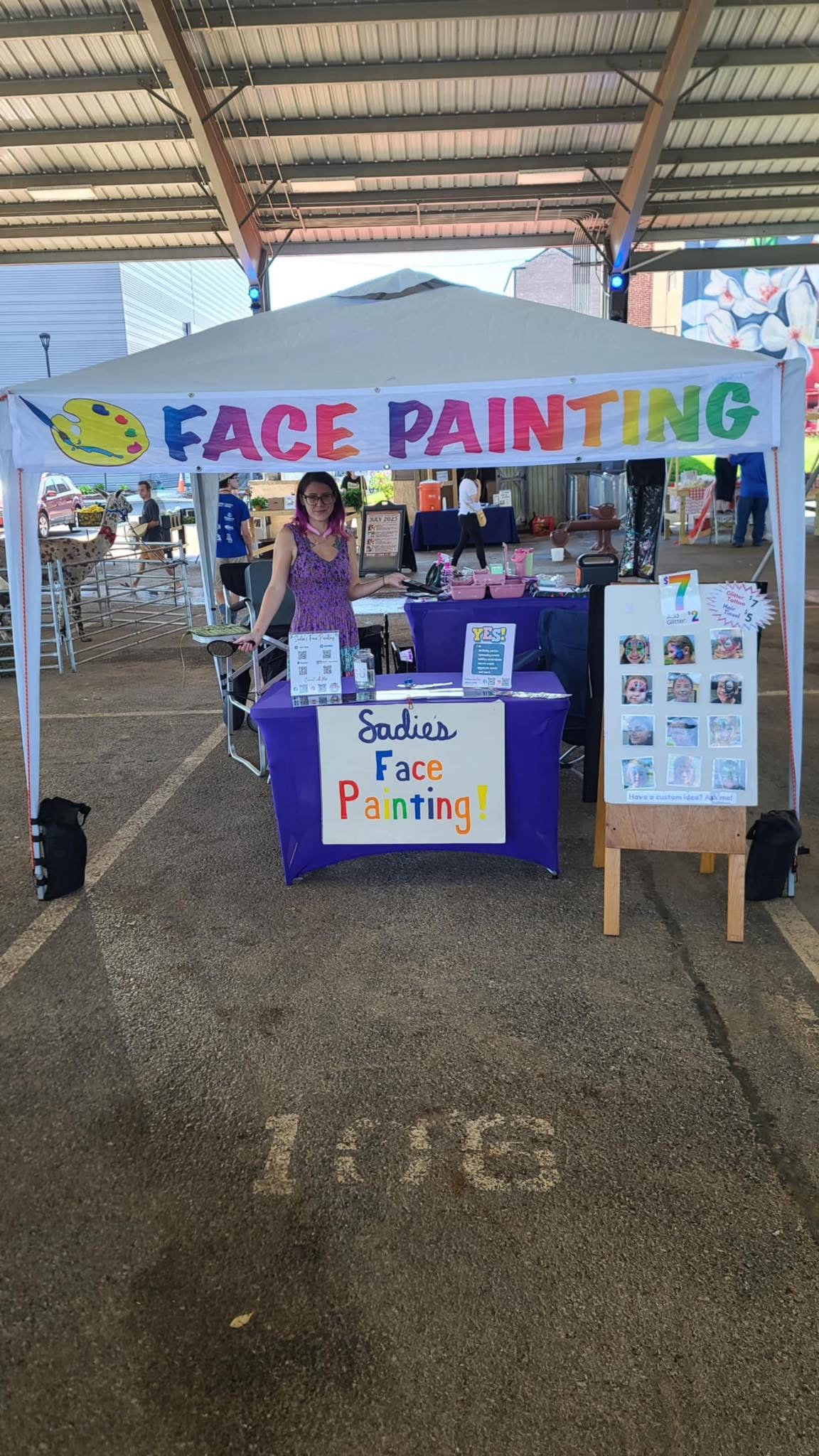Sadie's Face Painting full booth setup with branded tent and banner at a festival