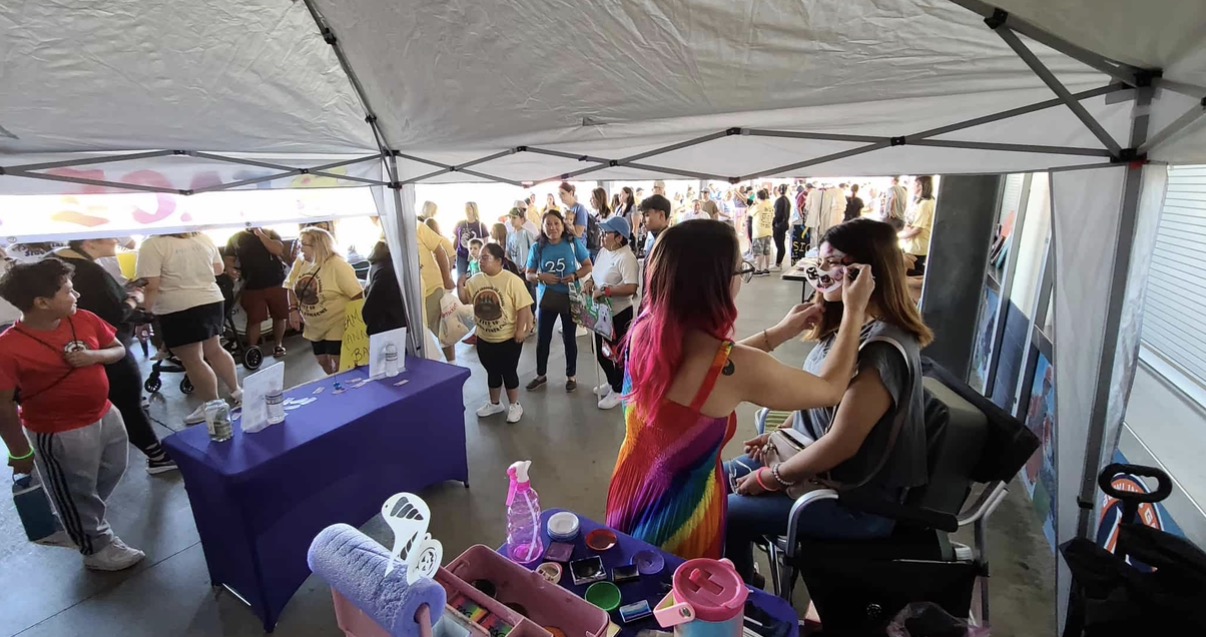 Sadie face painting at a busy walkathon event with a crowd behind her