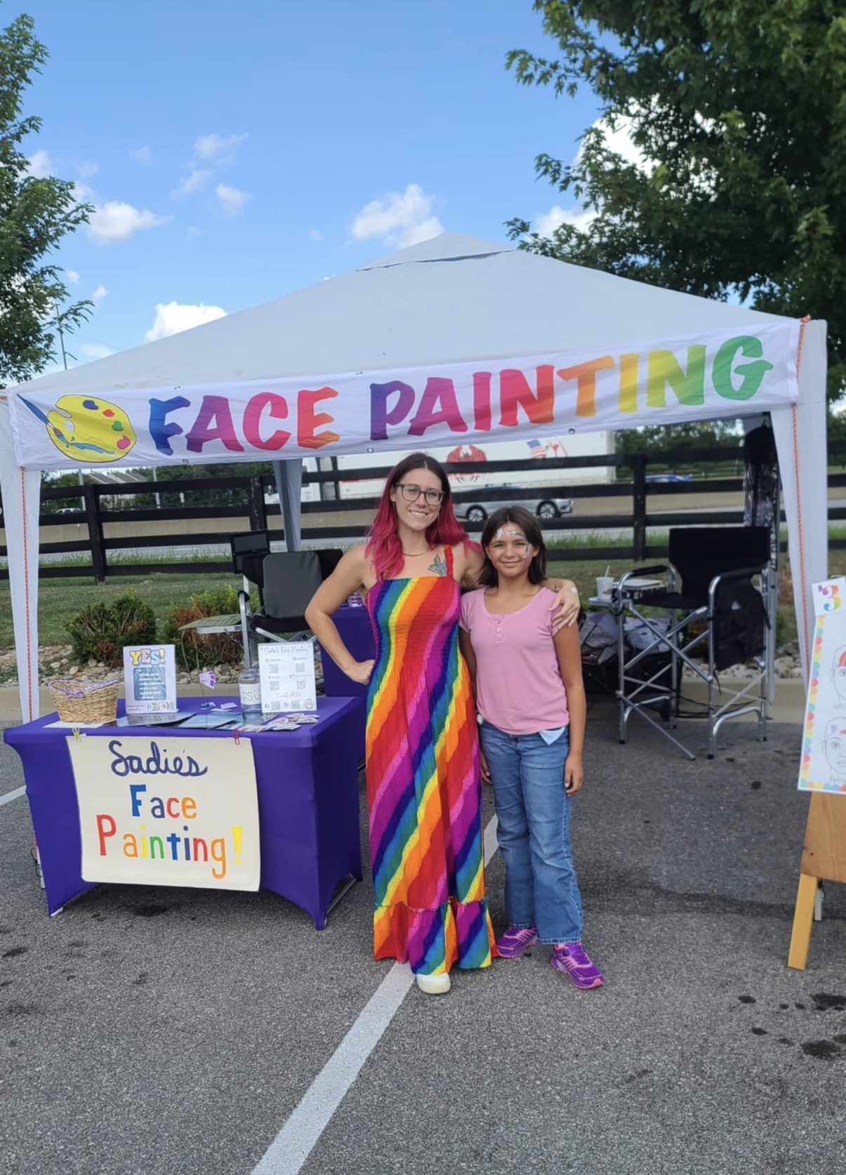 Sadie standing with a happy customer in front of her outdoor tent setup